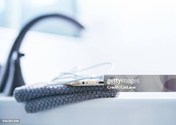 iphone 6s plus with charging cable on the side of a bathtub - iphone 6s imagens e fotografias de stock