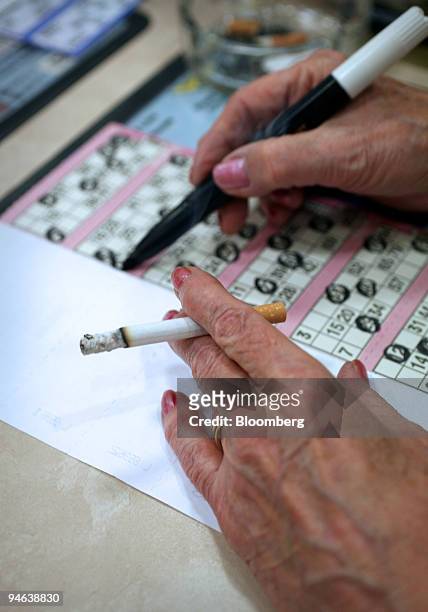 Woman smokes while marking her bingo card at Beacon Bingo in Cricklewood Broadway, north London, on Wednesday, December 13, 2006. Bingo parlors, once...