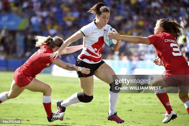 England's Emily Scarratt is tackled by Canada's Kayla Moleschi and Caroline Crossley in the women's rugby sevens bronze medal match at the Robina...