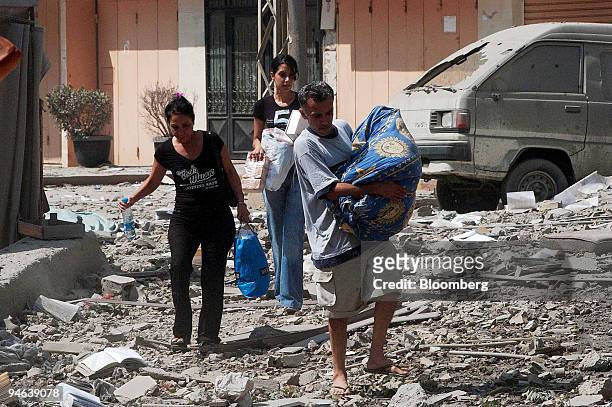Beirut residents carry their belongings through the ruins of buildings destroyed in an overnight air raid in Beirut, Lebanon, Saturday, August 5,...