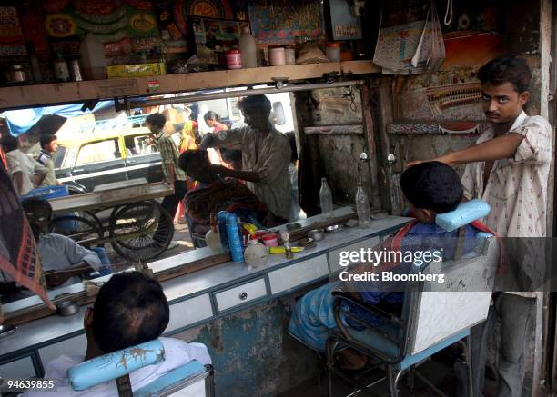 Barber shaves a customer in his open shop on a busy street in the Dharavi slum area of Mumbai, India, on Wednesday, June 6, 2007. The development...