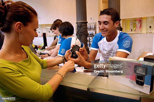 Salesman demonstrates a mobile phone to a customer in a 3Italia shop in Milan, Italy, Tuesday, Aug. 21, 2007. Hutchison Whampoa Ltd., billionaire Li...