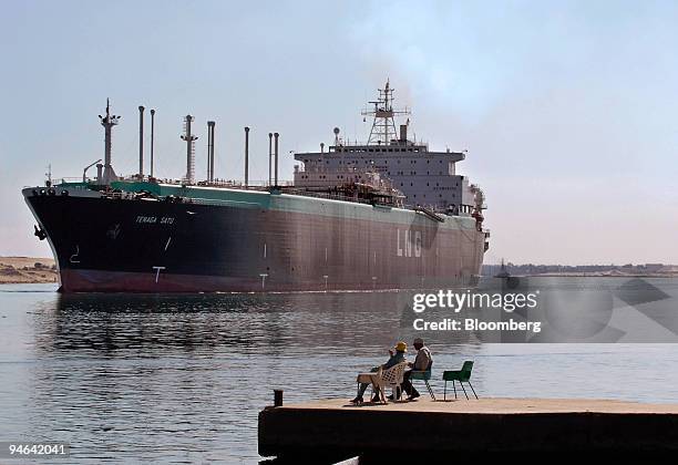 Men watch the Tenaga Satu, a Liquefied Natural Gas tanker owned by MISC Berhad, a Malaysian shipping company, as it sails northbound on the Suez...