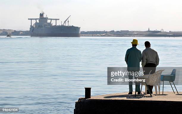 Men watch the Charles Eddie, a crude oil tanker owned by Euronav SA, a Belgian shipping company, sailing northbound on the Suez Canal in Ismailia,...