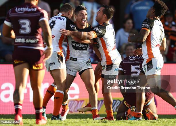 Malakai Watene-Zelezniak of the Tigers celebrates with team mates after scoring a try during the round six NRL match between the Manly Sea Eagles and...