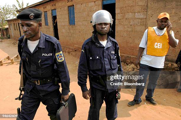 Congolese police and an election official stand in front of a polling station which was burnt down by a mob on election day in Mbuji-Mayi, East Kasai...
