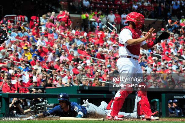 Orlando Arcia of the Milwaukee Brewers slides head first into home as Francisco Pena of the St. Louis Cardinals calls for the ball during the fifth...