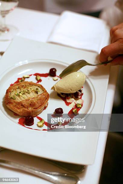 Chef adds a scoop of vanilla bean ice cream to the side of a pear and pistachio tart with brandied cherries at the new Dennis Foy restaurant, located...