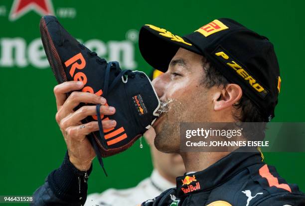 Red Bull's Australian driver Daniel Ricciardo drinks champagne out of his shoe as he celebrates on the podium after winning the Formula One Chinese...