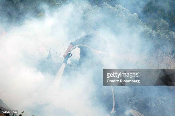 Man douses a fire caused by rockets that landed in an open area near Safed, in Upper Galilee, Israel, Friday, July 14, 2006. Israel pounded Hezbollah...