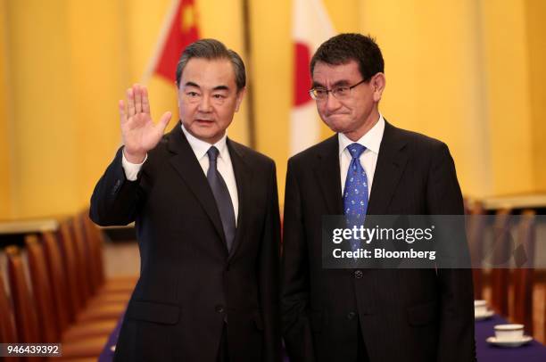 Wang Yi, China's foreign minister, left, waves as Taro Kono, Japan's foreign minister, looks on while standing for photographs ahead of a meeting in...