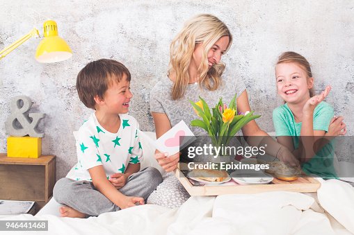 Mother´s Day - two children surprise their mother with breakfast in modern bed Mother´s Day - two children surprise their mother with breakfast in modern bed