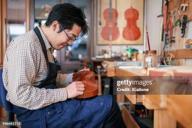 craftsman repairing a blemish on an antique violin - musical instrument repair stock pictures, royalty-free photos & images