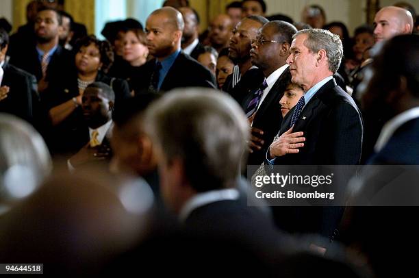 President George W. Bush places his hand over his heart as a choir sings "God Bless America" during a celebration in honor of African American...