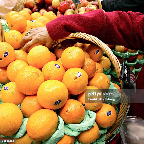 Shopper reaches for an orange at a grocery store in New York, Thursday, December 07, 2006. Orange-juice prices rose to a record of $2.094 a pound on...