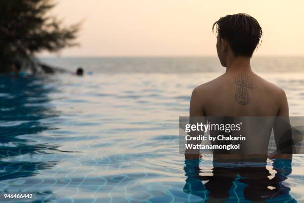 a young man enjoy sunset and sea in the pool by the sea. - chanthaburi sea fotografías e imágenes de stock