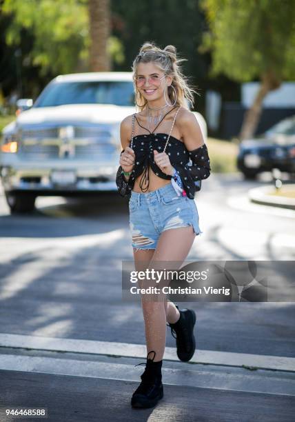 Xenia van der Woodsen wearing cropped off shoulder top, denim shorts, backpack, boots is seen at Revolve Festival on April 14, 2018 in Indio,...
