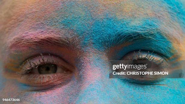 Participant with her face covered with coloured powder poses for a photograph as runners celebrate after completing their five kilometers in the...
