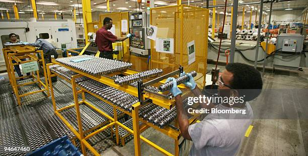 Yemane Tesfamir, right, loads camshafts for General Motors' GEN4 V8 engines, bound for GM sport utility vehicles, into racks to send them for final...