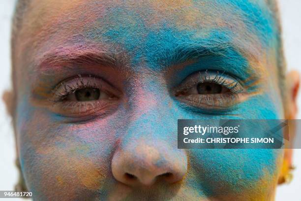 Participant with her face covered with coloured powder poses for a photogaph as runners celebrate after completing their five kilometers in the Color...