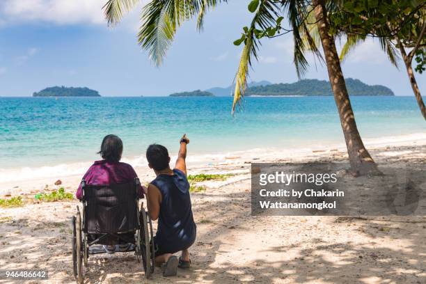 a lonely senior woman sitting on wheelchai on the beach with blue sea. - socorro island imagens e fotografias de stock