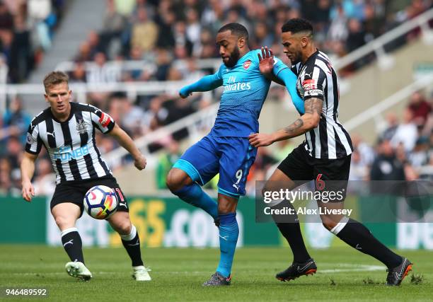 Alexandre Lacazette of Arsenal, Jamaal Lascelles of Newcastle United and Matt Ritchie of Newcastle United battle for possession during the Premier...