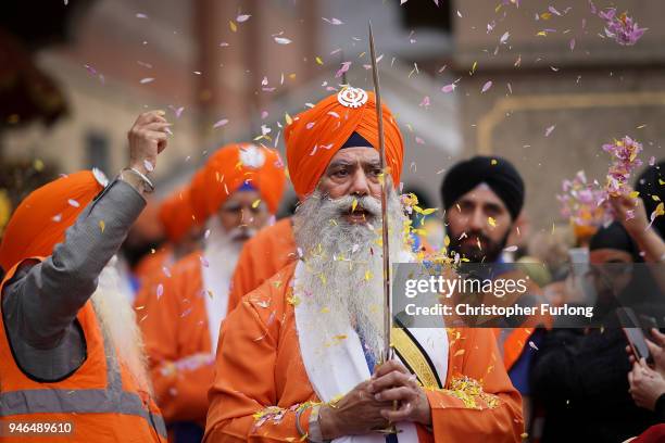 Sikh devotees of the Guru Nanak Sikh Gurdwara community throw flower petals as sword bearers parade through the streets of Walsall to celebrate...