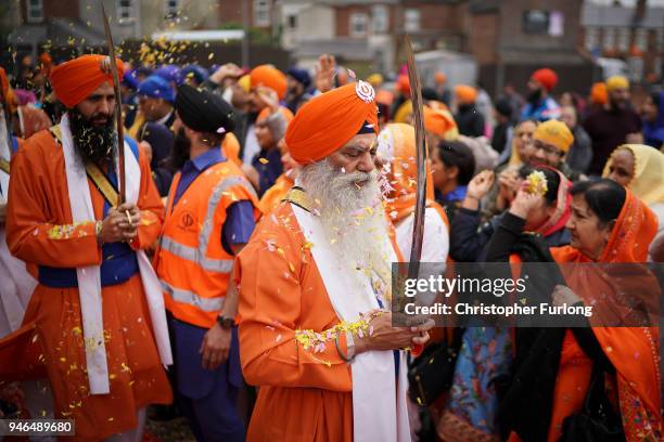 Sikh devotees of the Guru Nanak Sikh Gurdwara community throw flower petals as sword bearers parade through the streets of Walsall to celebrate...