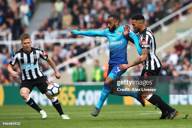 Alexandre Lacazette of Arsenal is challanged by Jamaal Lascelles of Newcastle United and Matt Ritchie of Newcastle United when battleing for...