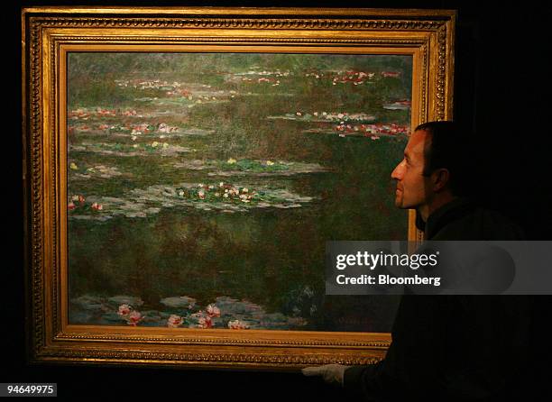 Sotheby's employee steadies Claude Monet's 1904 painting entitled ''Nympheas'' at Sotheby's in London, U.K., Tuesday, June 5, 2007. The painting,...