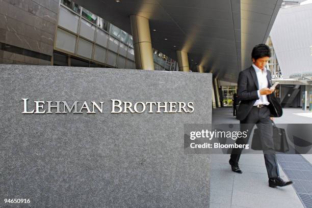 Man walks past a sign for Lehman Brothers Inc. In the Roppongi Hills district of central Tokyo, Japan, on Thursday, May 24, 2007. Lehman Brothers...