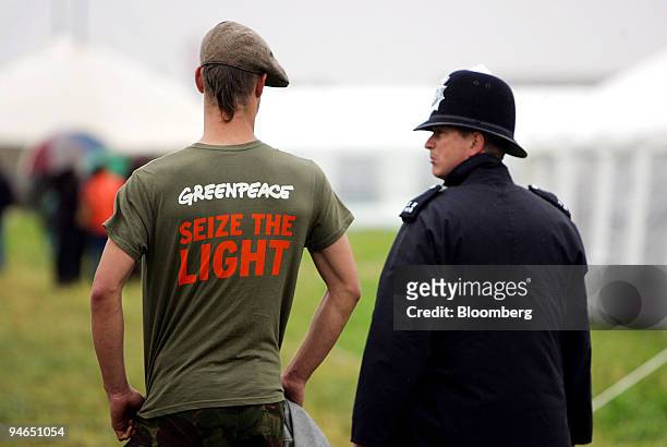 Protestor and a police officer stand together at the climate change action camp alongside Heathrow airport, near London, U.K., Tuesday, Aug. 14,...