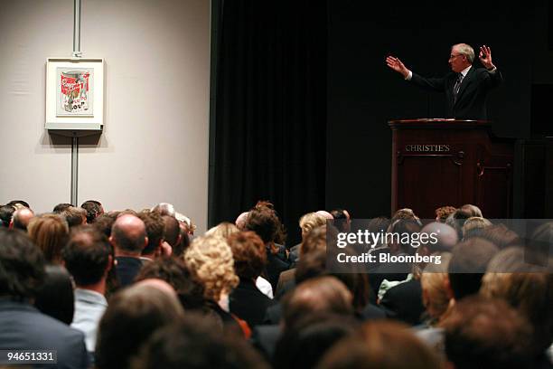Christopher Burge, auctioneer and honorary chairman of Christie's, right, acknowledges a bid for Andy Warhol's painting entitled "Small Torn...