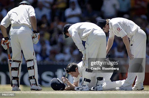 Alastair Cook, center, fielding for England, is attended to by team mates Geraint Jones, second right and Paul Collingwood, right, after being struck...