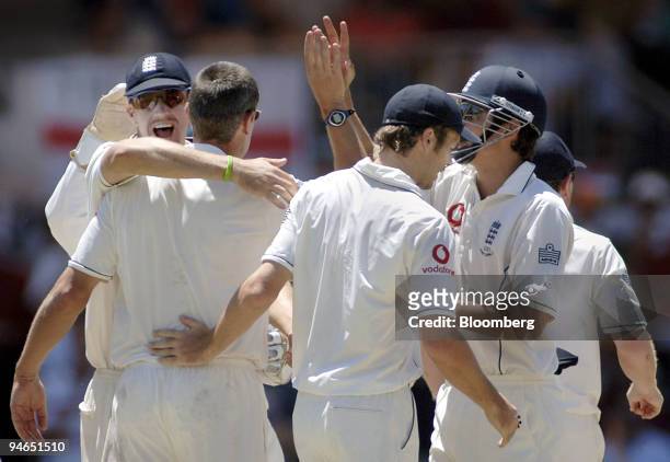 England fielders, including Kevin Pietersen, left, rush to congratulate bowler Ashley Giles, second left, after Giles claimed the wicket of Adam...