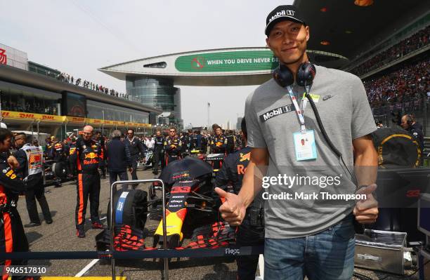 Chinese basketball player Yi Jianlian poses for a photo with the car of Max Verstappen of Netherlands and Red Bull Racing on the grid before the...