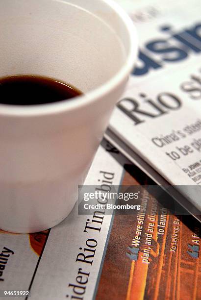 Cup of coffee sits atop a pile of newspapers with headlines on the takeover bid for Rio Tinto Group, in Melbourne, Australia, on Wednesday, Dec. 5,...