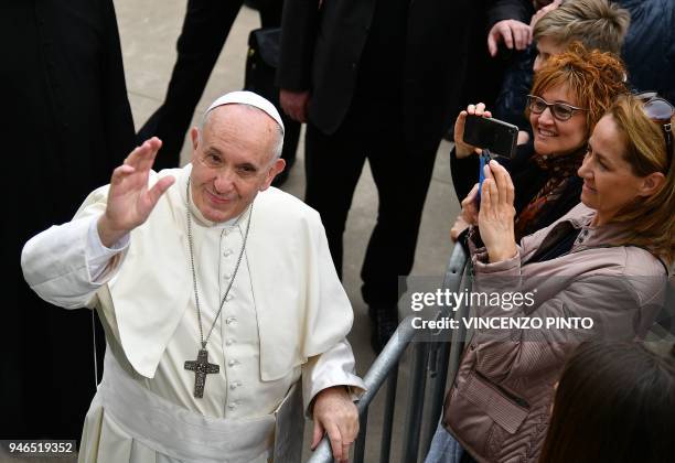 Pope Francis waves to people as he arrives at the Parish of Saint Paul of the Cross in Corviale, southwest of Rome, for a pastoral visit on April 15,...