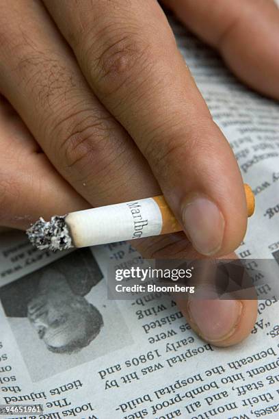 Man smokes a Marlboro cigarette while reading the newspaper outside his downtown Boston, Massachusetts office on Tuesday, July 25, 2006. Altria Group...