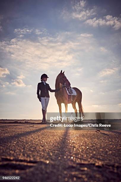 a young woman standing with her horse on the beach - jodhpurs stock pictures, royalty-free photos & images