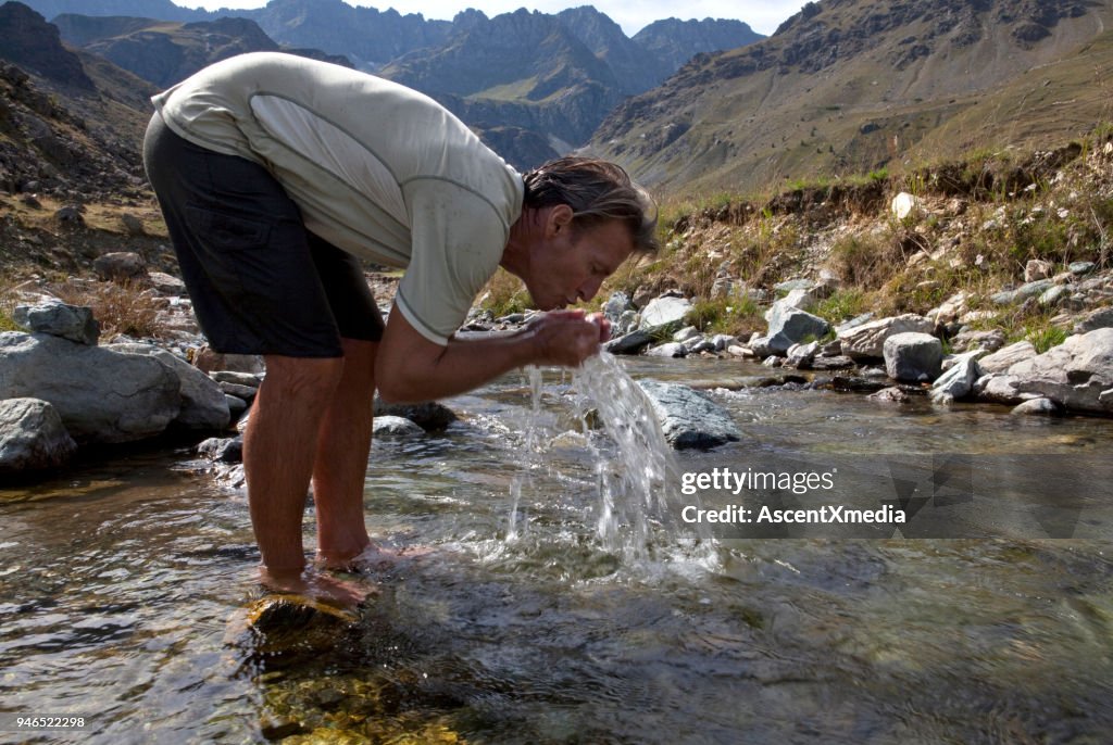 Mann spritzt Gesicht in klaren Gebirgsbach, Piemont, Italien