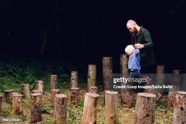 father walking his son along some cut tree stumps - balin stock pictures, royalty-free photos & images