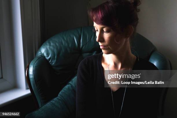 woman sitting on chair looking down at the floor - balin stock pictures, royalty-free photos & images