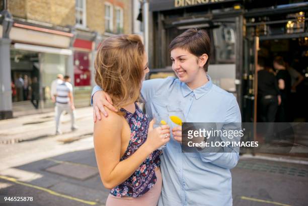 a young lesbian couple enjoy a drink in the sunshine - bar tender photos et images de collection