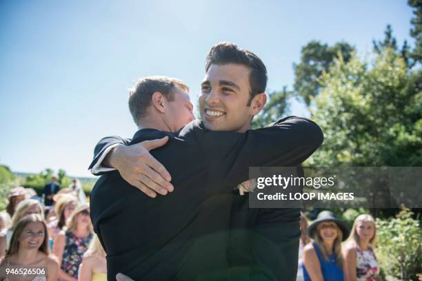 a groom and best man share a hug prior to the wedding service - best man stock pictures, royalty-free photos & images
