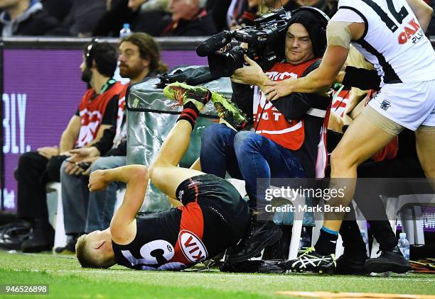 Matt Guelfi of the Bombers crashes into a cameraman during the round four AFL match between the Essendon Bombers and the Port Adelaide Power at...