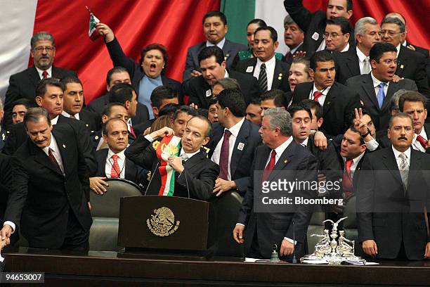 Mexican President Felipe Calderon, center, puts on his sash during his inauguration with former President Vicente Fox, left, at Mexico's Congress in...