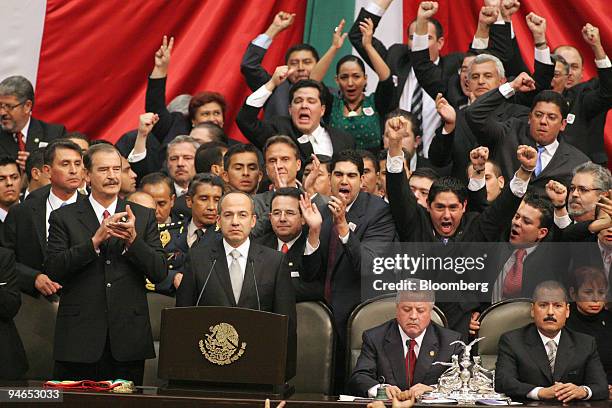 Mexican Legislators cheer and yell as Mexican President Felipe Calderon, center, takes the oath of office with former President Vicente Fox, left, at...