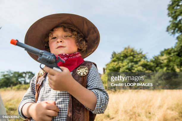 a young boy plays cowboys and indians outside in the sunshine - boyhood film stock-fotos und bilder