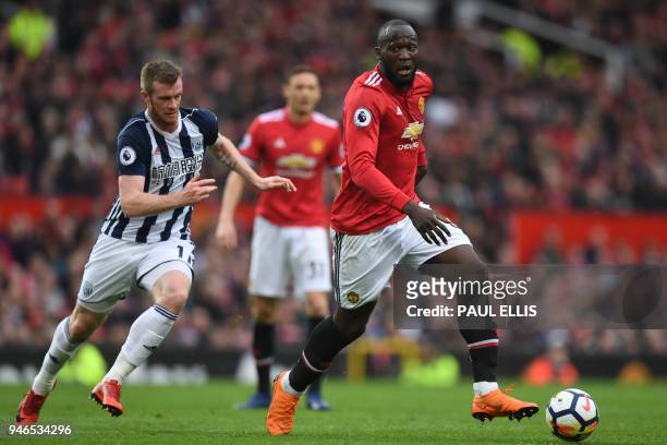 Manchester United's Belgian striker Romelu Lukaku shields the ball from West Bromwich Albion's Northern Irish midfielder Chris Brunt during the...